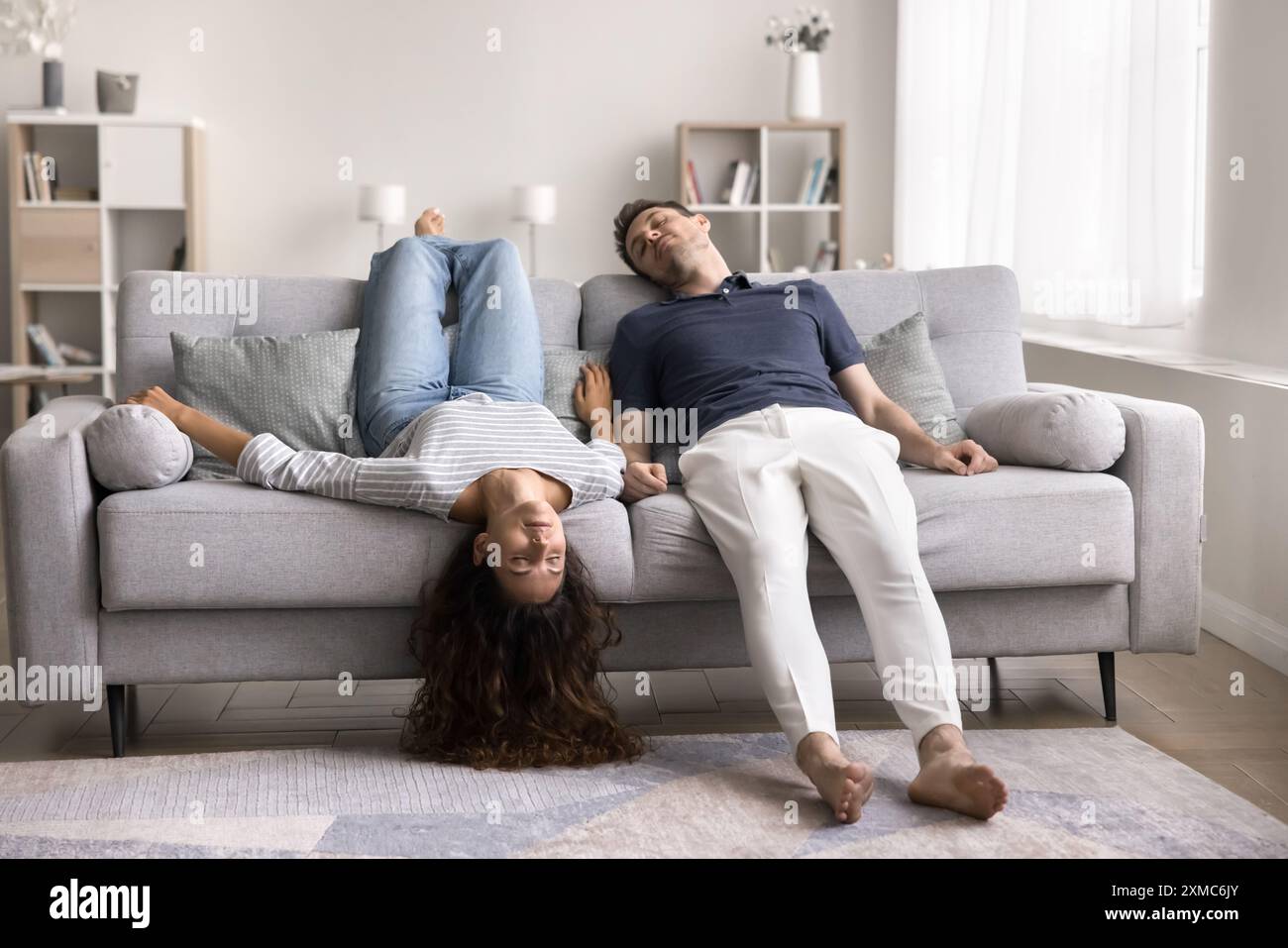 Sleeping young couple lying upside down on sofa Stock Photo