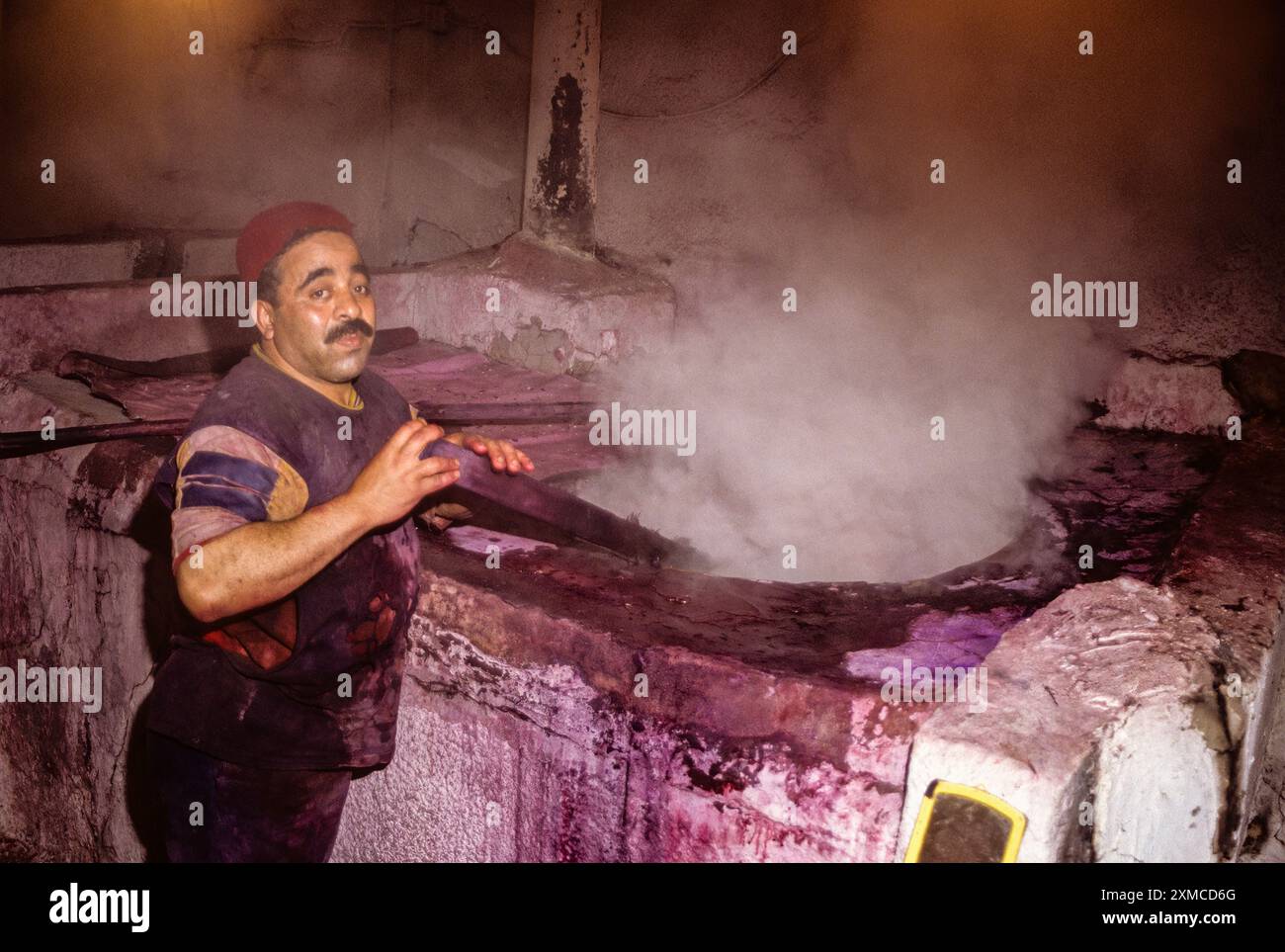 Tunisian Hat, Chechia.  Steam Surrounds Worker Stirring Vat of Boiling Dye in Chechia Workshop. Stock Photo