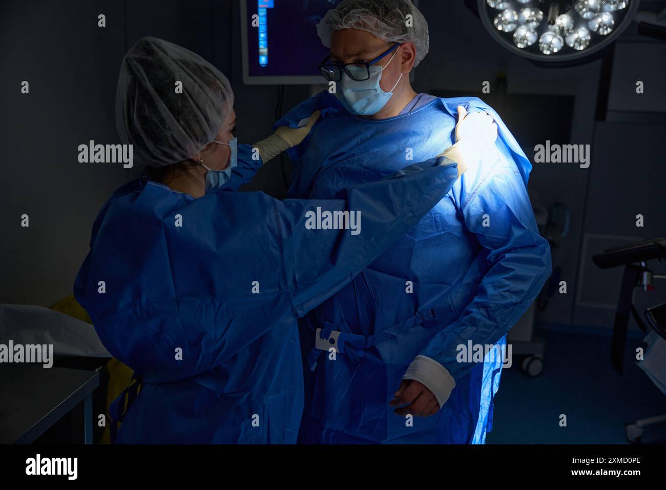 Medical assistant helping surgeon putting on uniform in an operating ...
