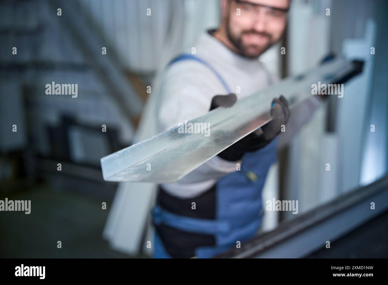 Man in work overalls holds aluminum profile in his hands Stock Photo