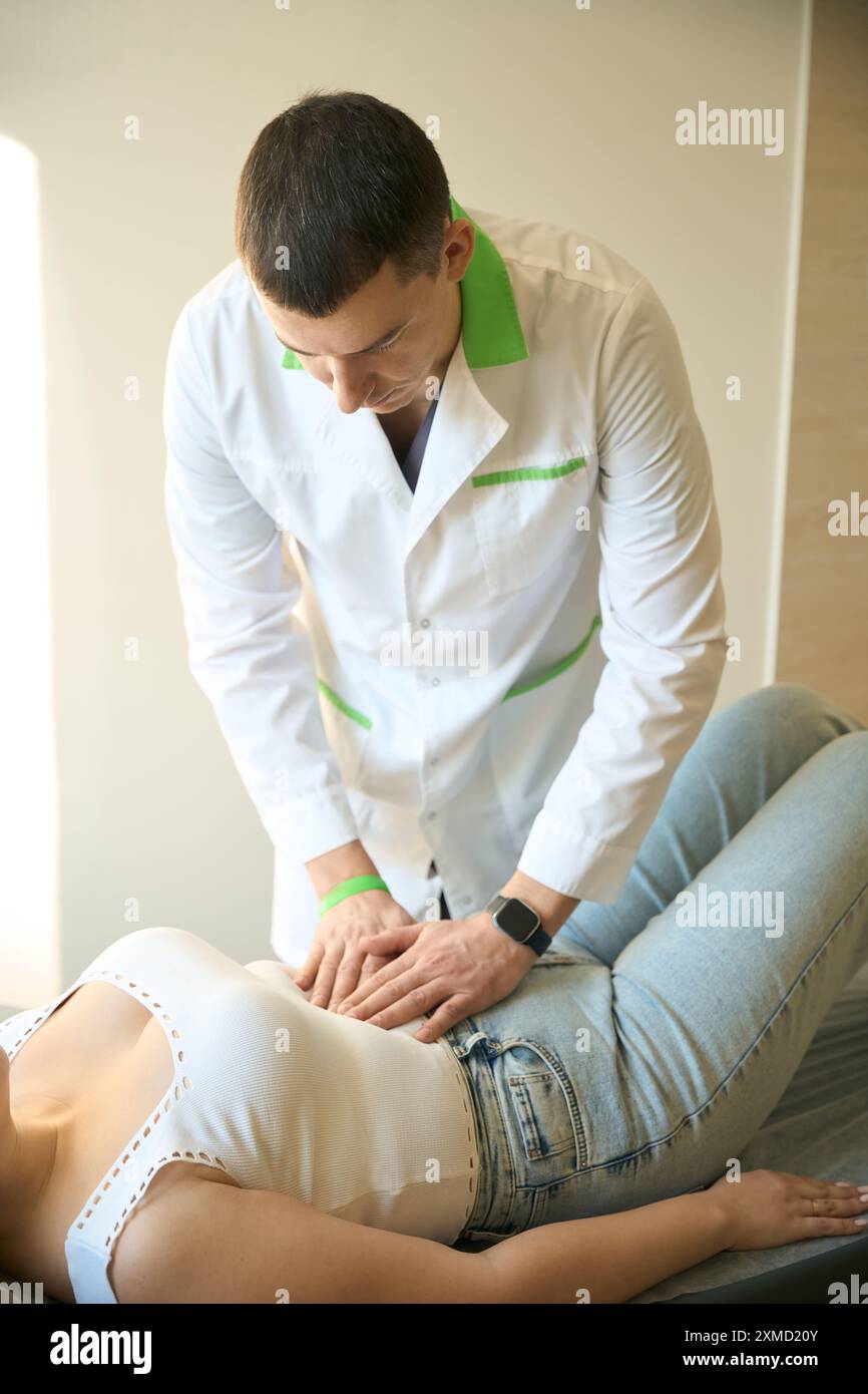 Surgeon carrying out abdominal palpation of adult woman Stock Photo