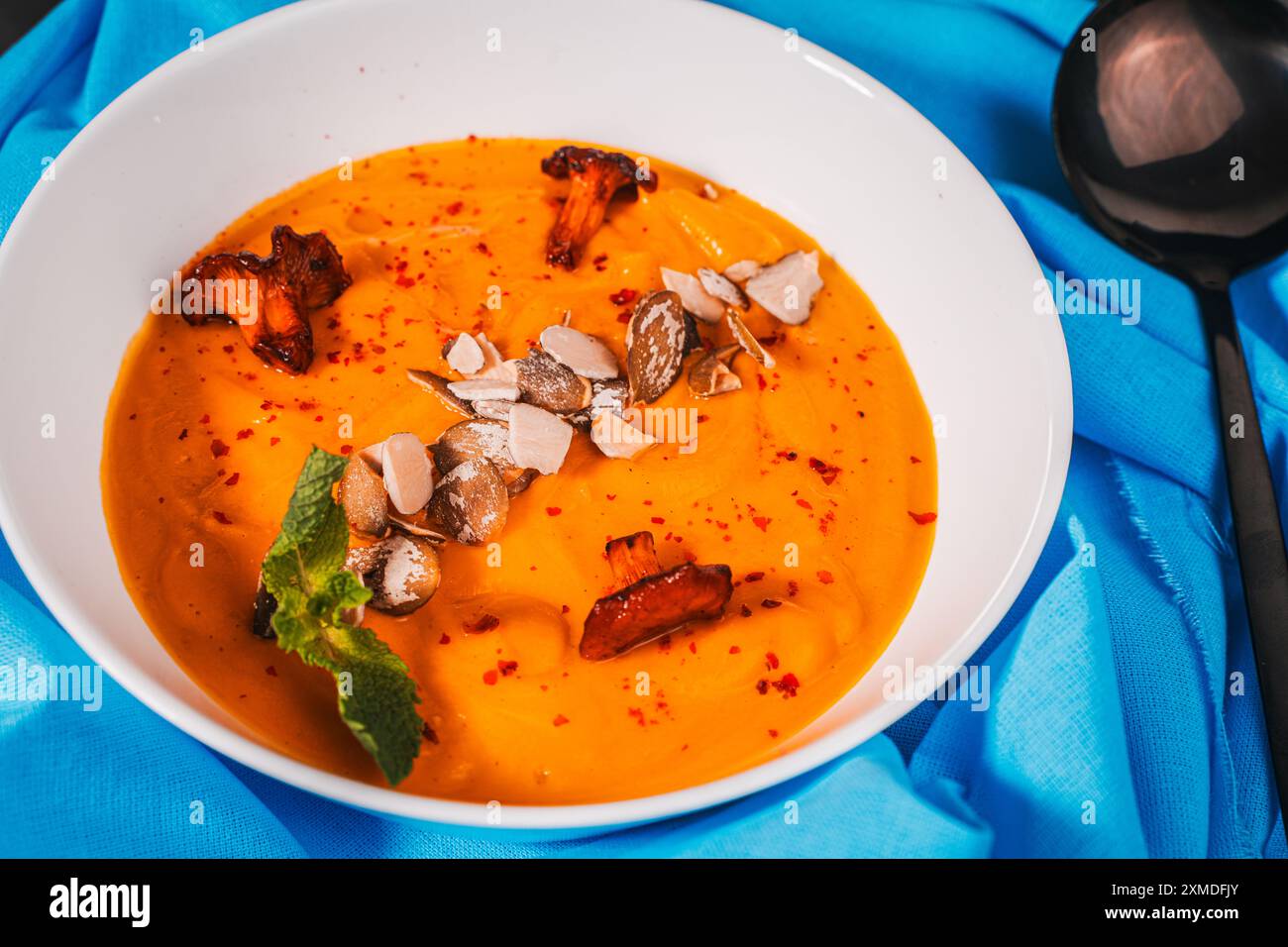 Pumpkin and carrot puree soup with seeds and mushrooms Chanterelles on a blue napkin. High quality photo Stock Photo