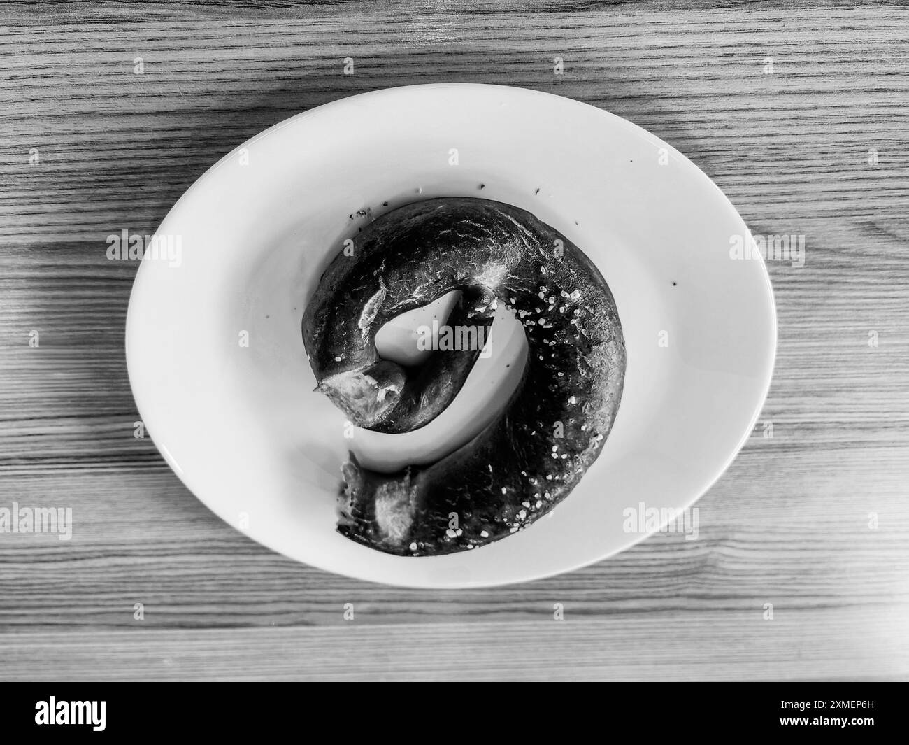 Number 9.  Pretzel on a White Plate: Breakfast Time on a Wooden Table. Black and white. Stock Photo