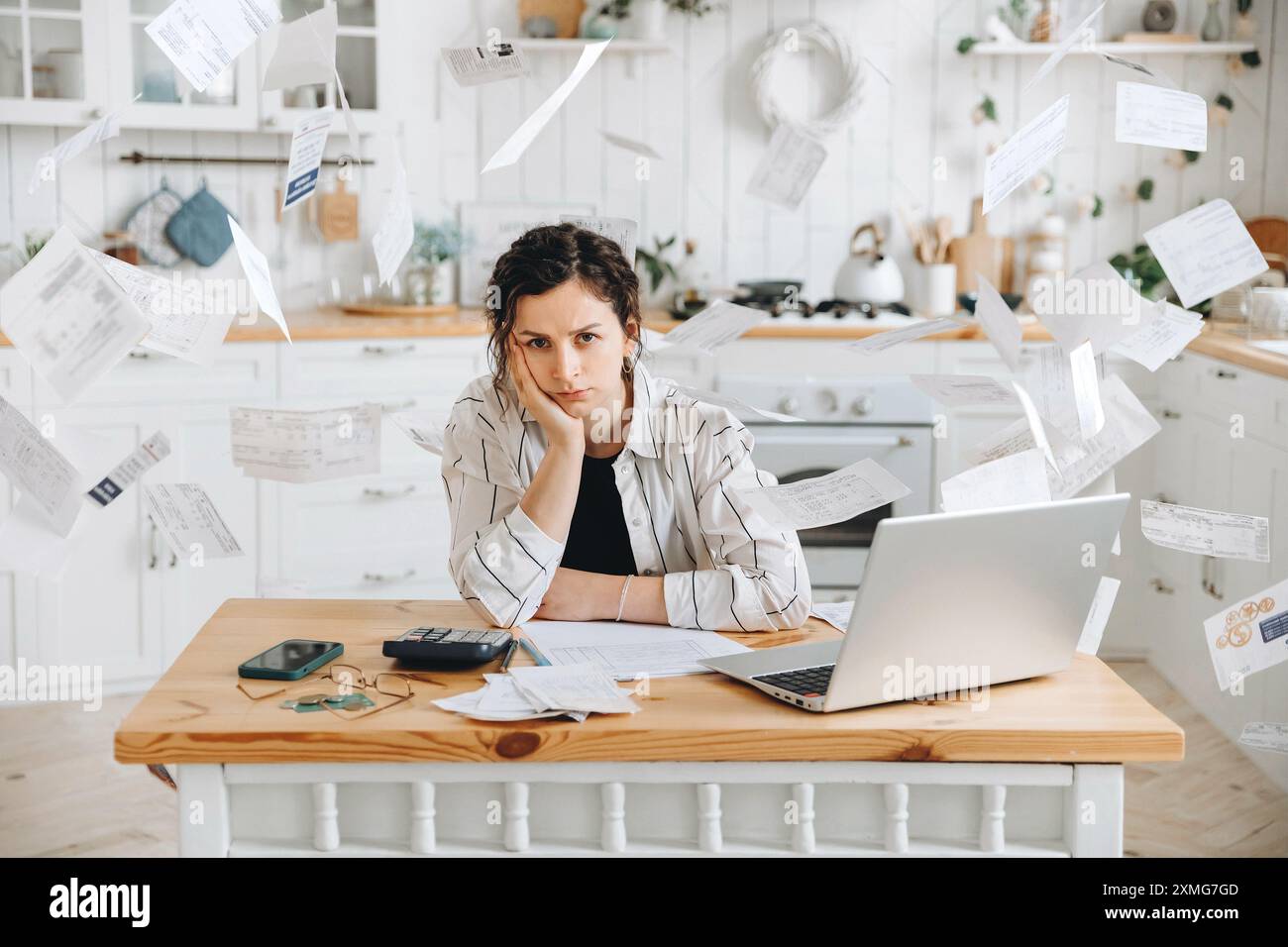 Stressed woman trying to deal with financial documents, having problem to find money to pay utility bills or loans. Receipts and bills rain down on th Stock Photo