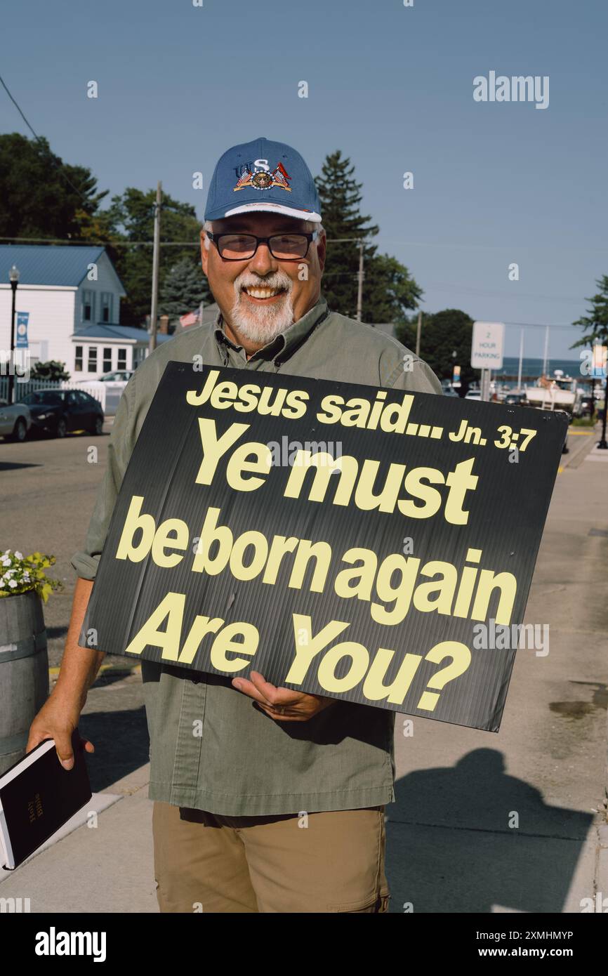 Man holding sign with religious message with Bible verse and asking about being born again, in Port Sanilac Michigan USA Stock Photo