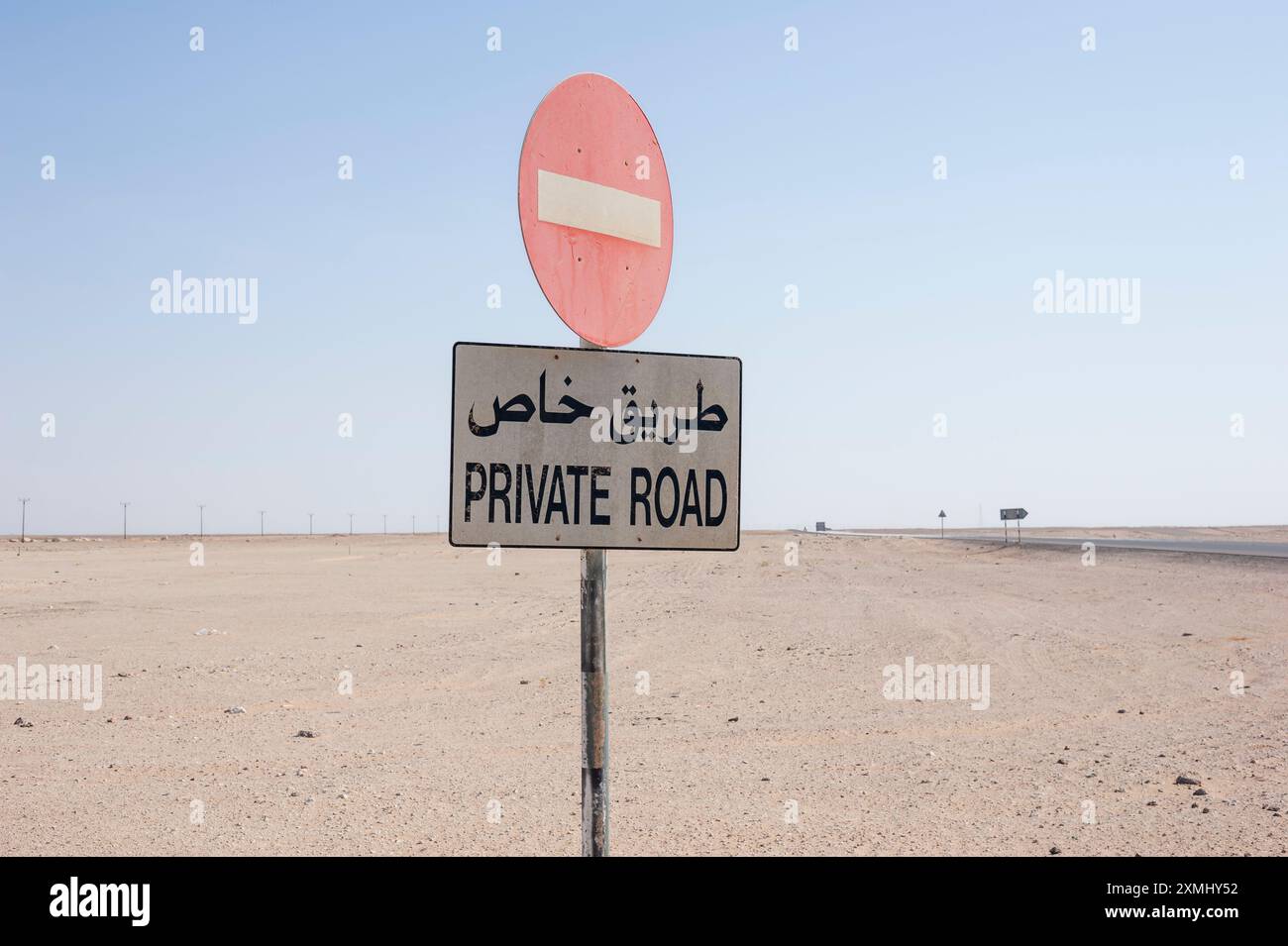 Private road in Oman's desert with no-entry signs and bilingual ...