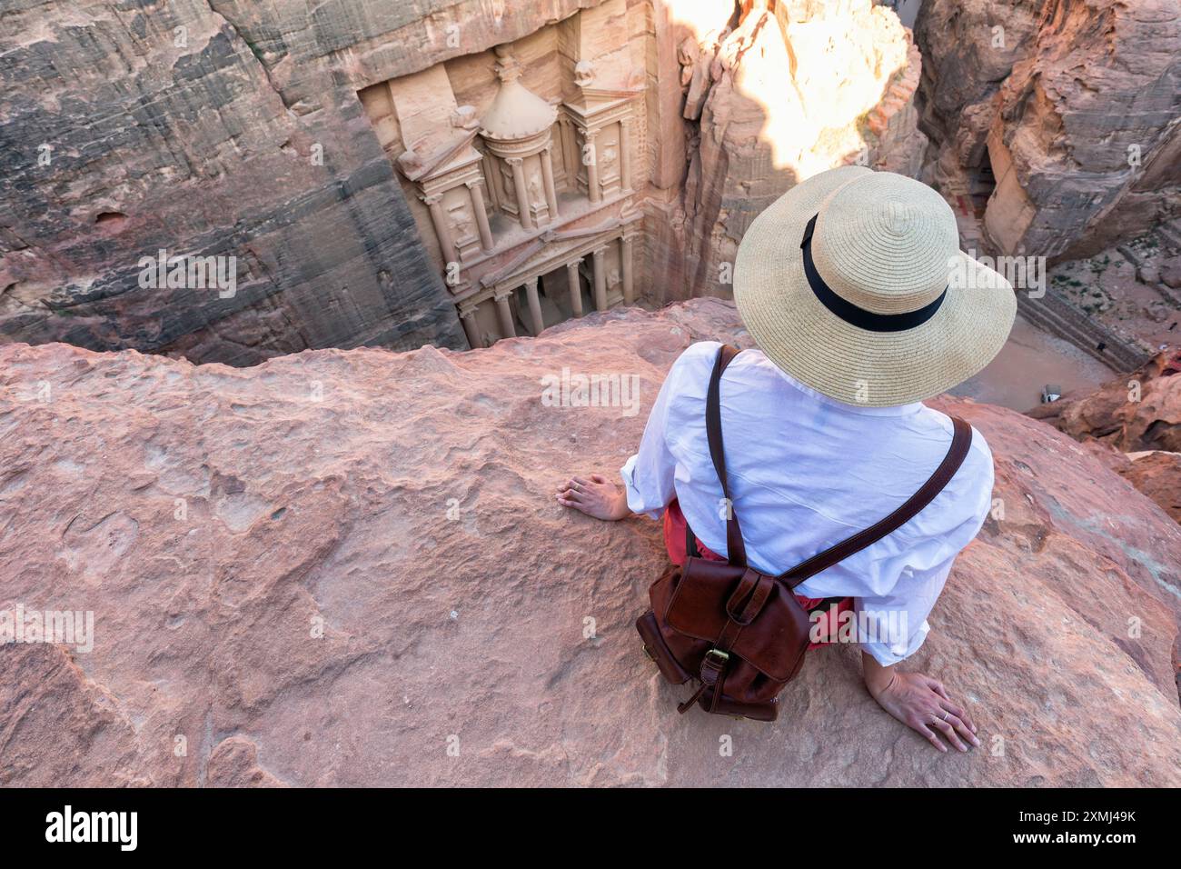 Woman traveler sitting on carpet viewpoint in Petra ancient city looking at the Treasury or Al-khazneh, famous travel destination of Jordan and one of Stock Photo