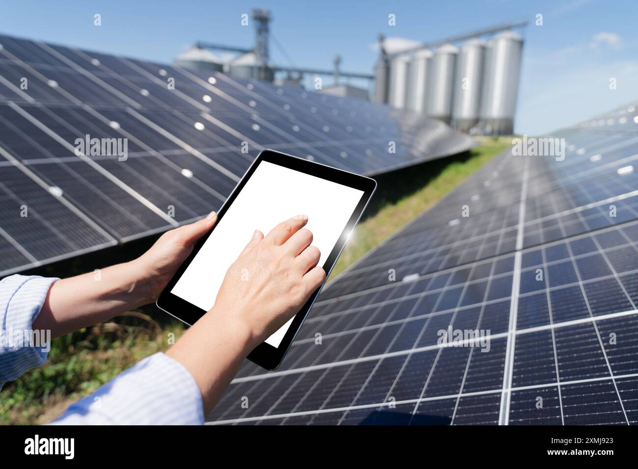 Hands with digital tablet on a background of modern farm using renewable energy. . Stock Photo