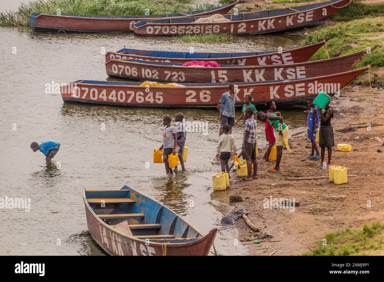 KATUNGURU, UGANDA - MARCH 16, 2020: Children collect water from Kazinga Channel in Katunguru village, Uganda Stock Photo