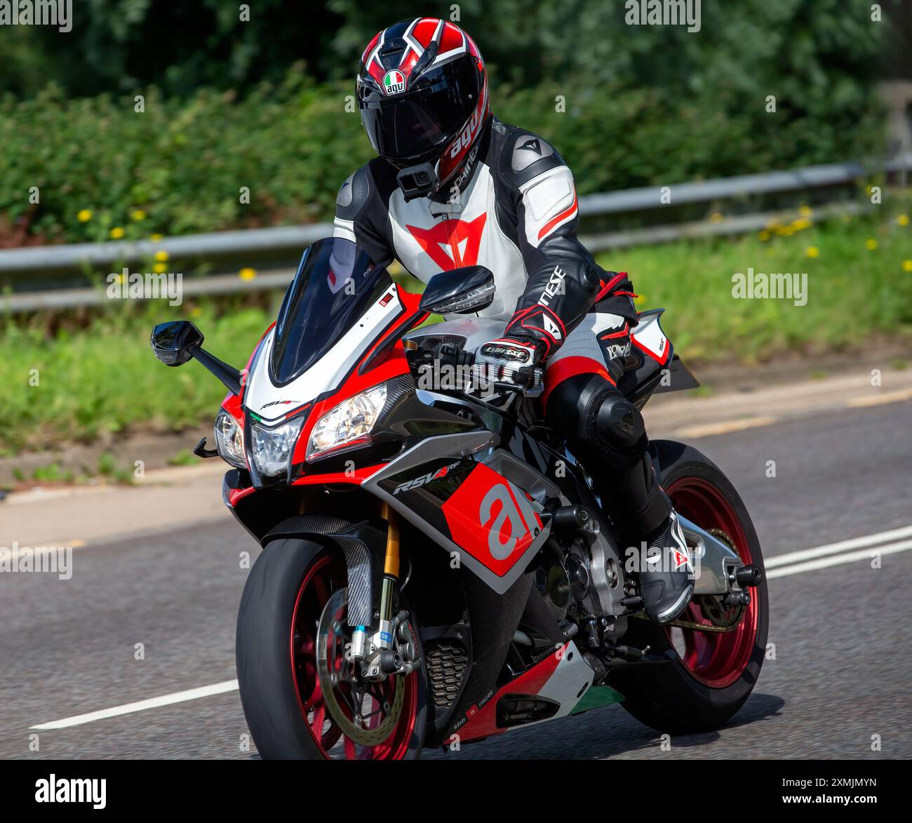 Milton Keynes,UK - July 28th 2024: Man wearing brightly colored full leather motorcycle suit riding a 2015 Aprilia RSV motorcycle on a British road Stock Photo