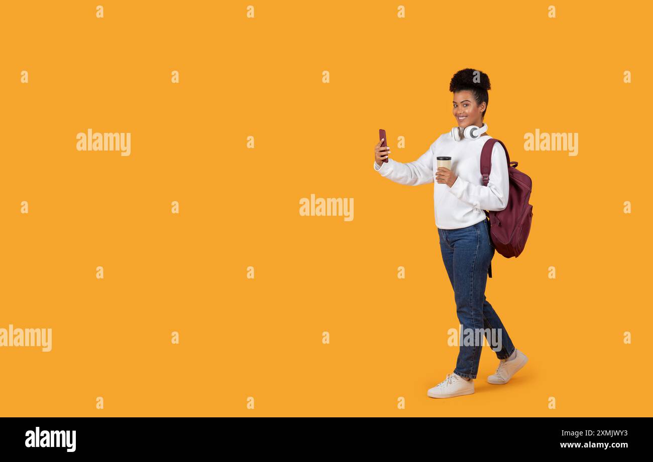 Young Woman Taking Selfie While Walking With Backpack and Coffee Stock Photo