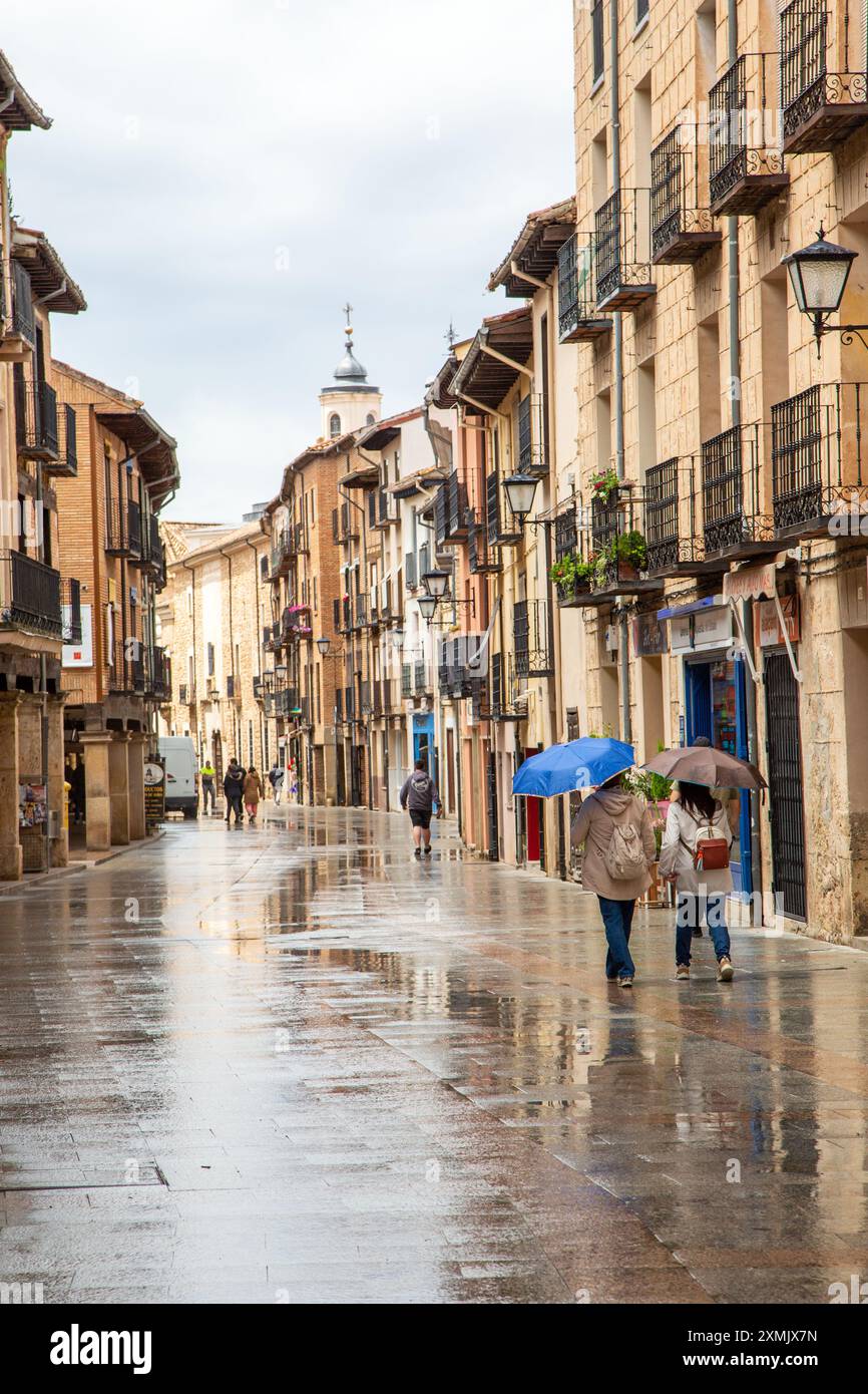 People walking in the rain and wet weather in the Spanish medieval walled city of El Burgo de Osma in the Province of soria Castile and Leon Spain Stock Photo