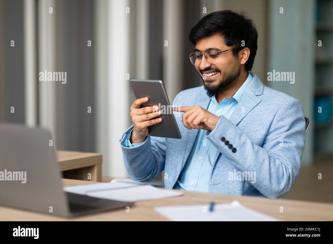 Smiling Indian Man Using Tablet In Office Stock Photo