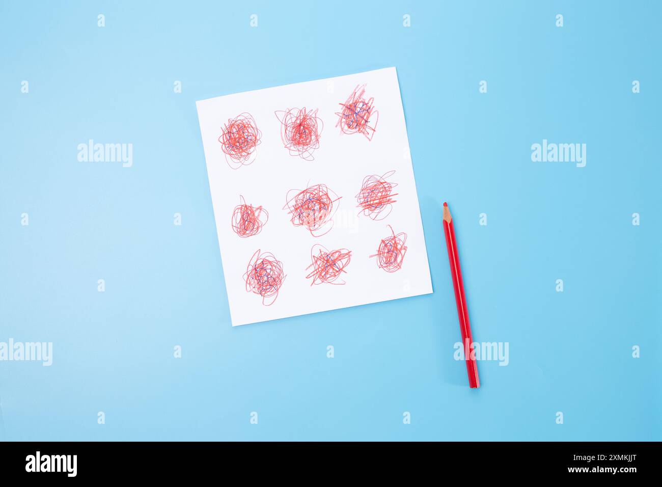 a red pencil and piece of paper with a child's drawing, part of process ...