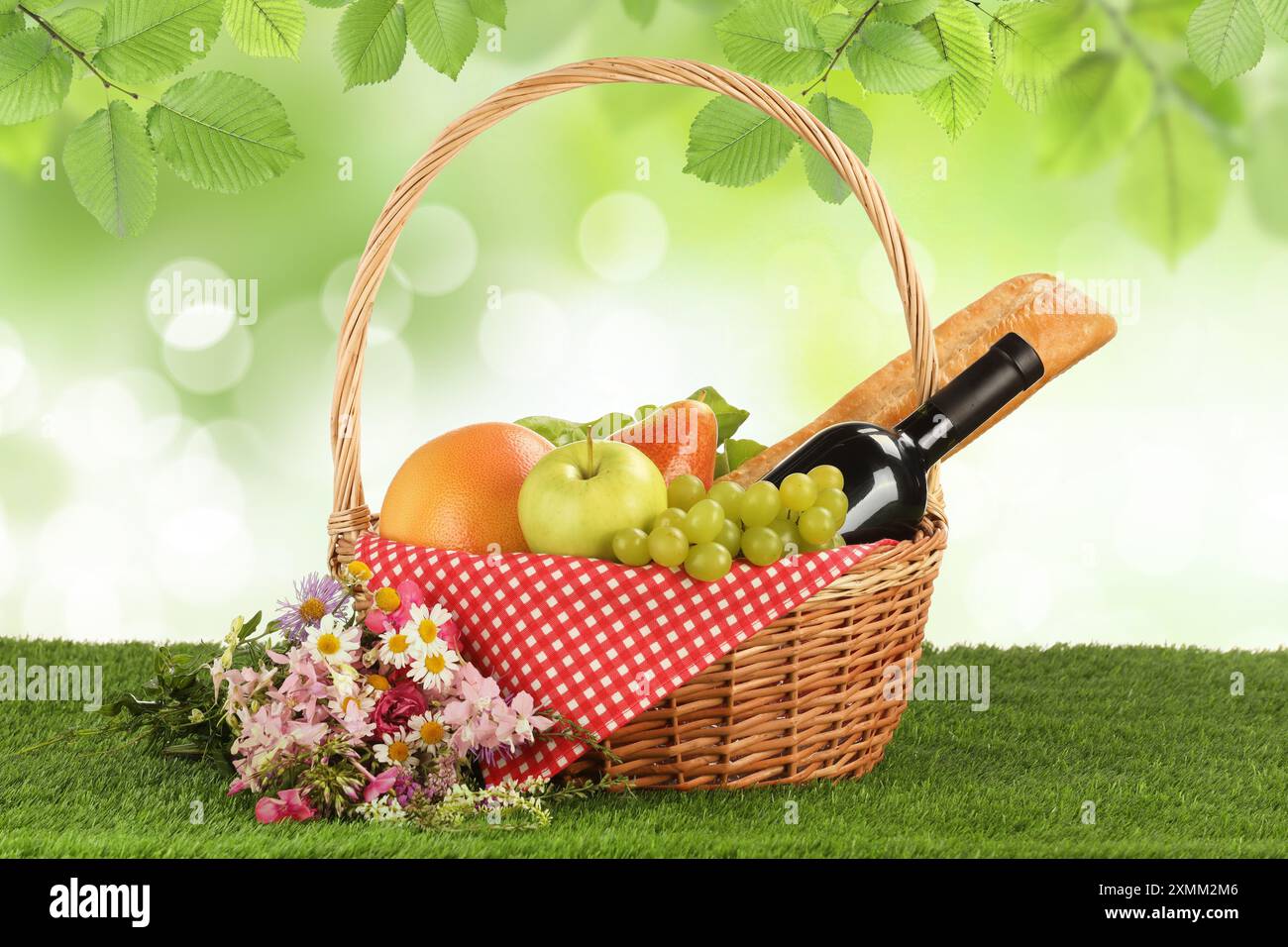Picnic basket with foods and wine on green grass outdoors Stock Photo ...