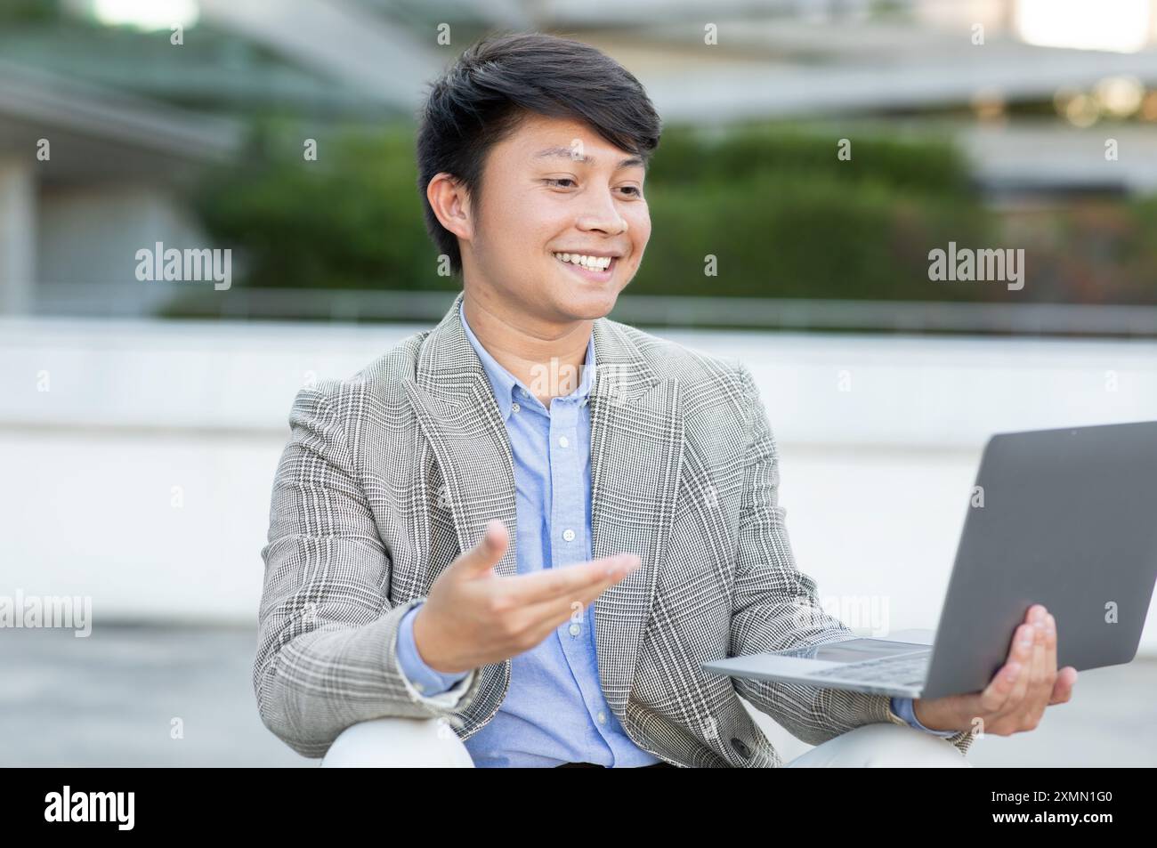 Smiling Young Man Using Laptop Computer Outdoors During Daytime Stock Photo