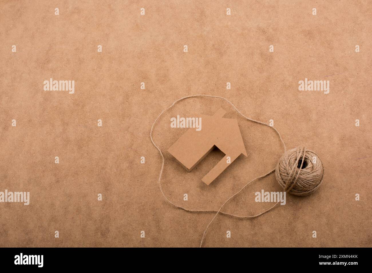 House shape cut out of paper and spool of thread brown background Stock ...