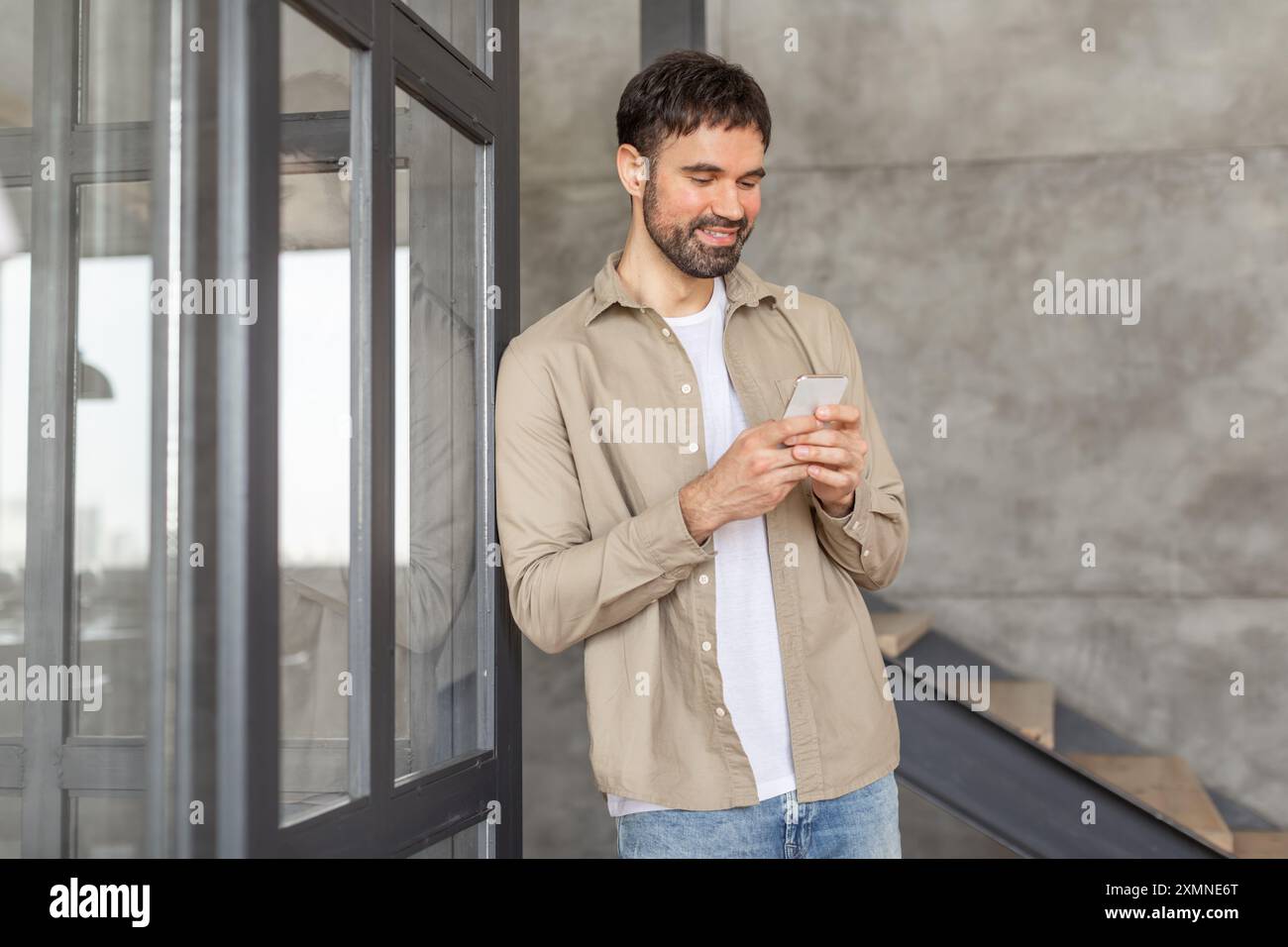 Smiling Man Using Smartphone Near Modern Building Stock Photo