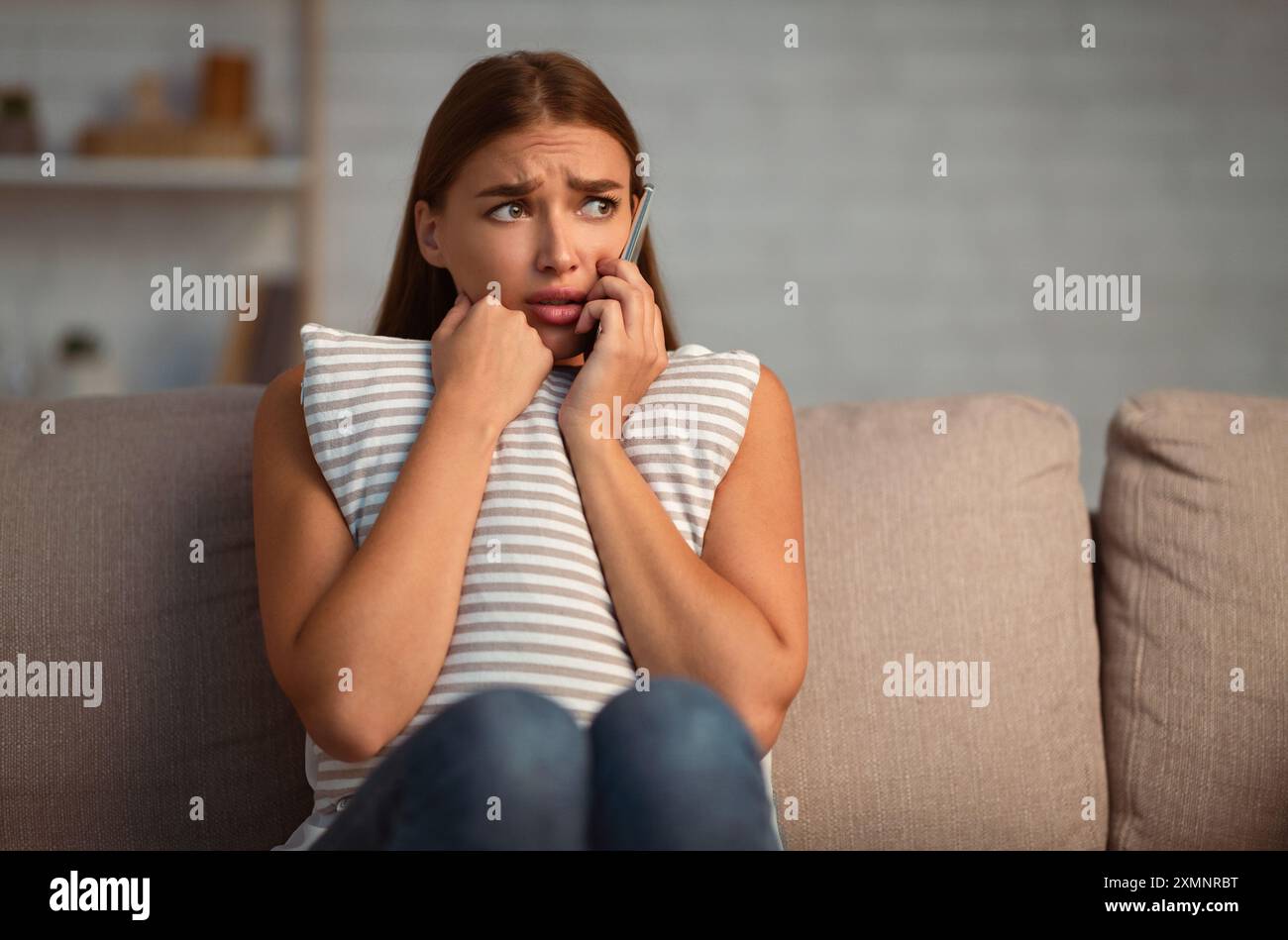 Scared Woman Calling The Police Sitting On Couch At Home Stock Photo