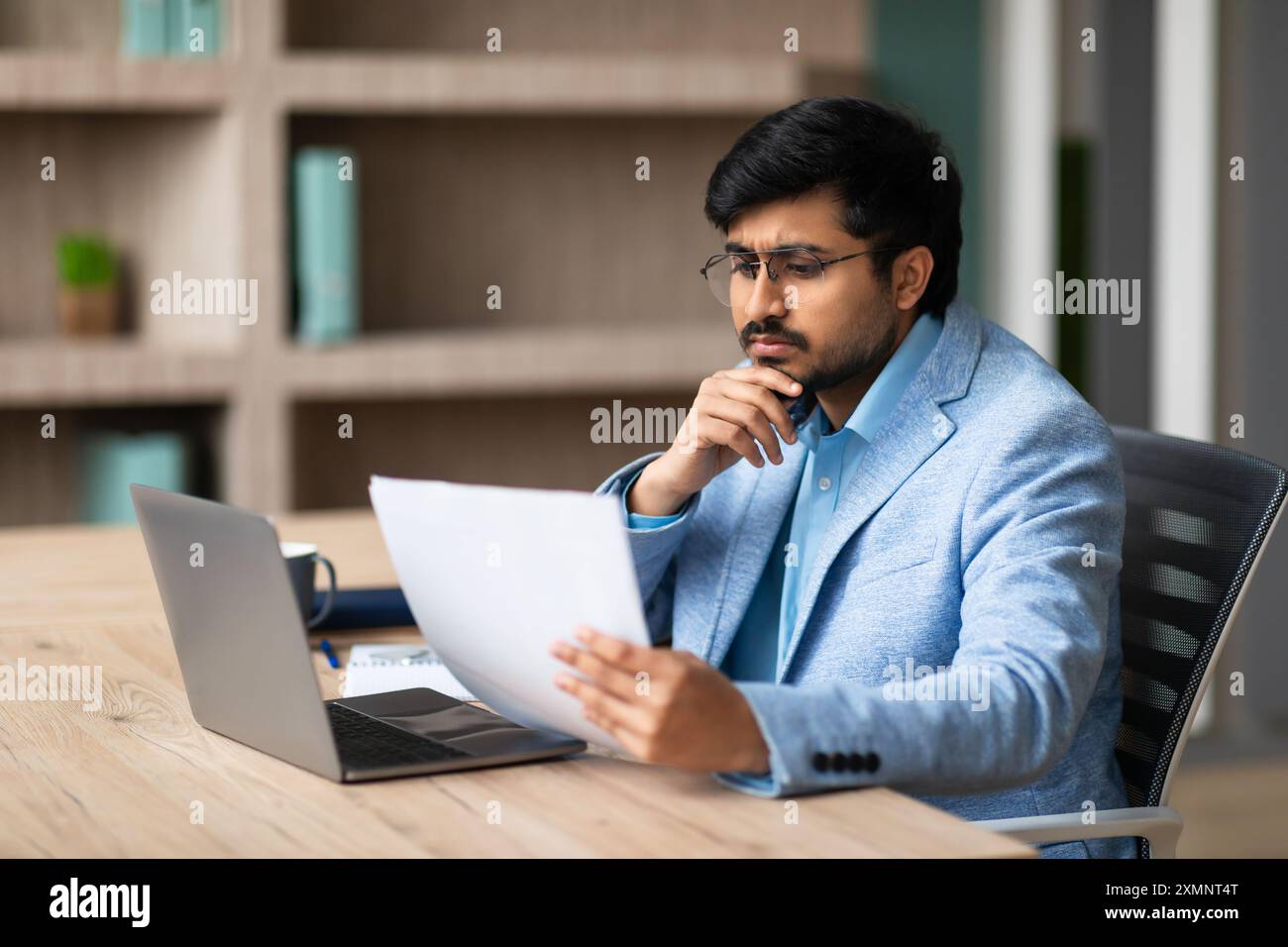 Businessman Reading Documents at Desk in Office Stock Photo