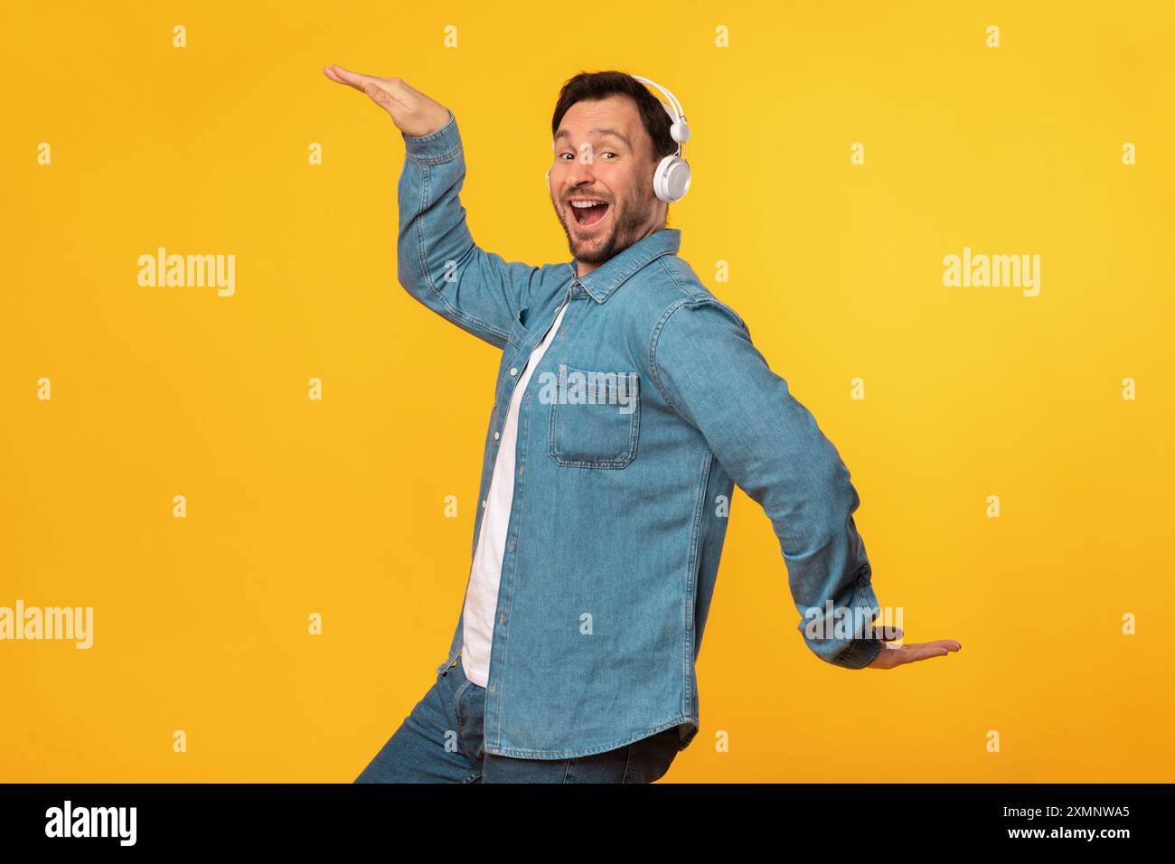 Happy Man Dancing Over Yellow Background While Wearing Headphones Stock Photo