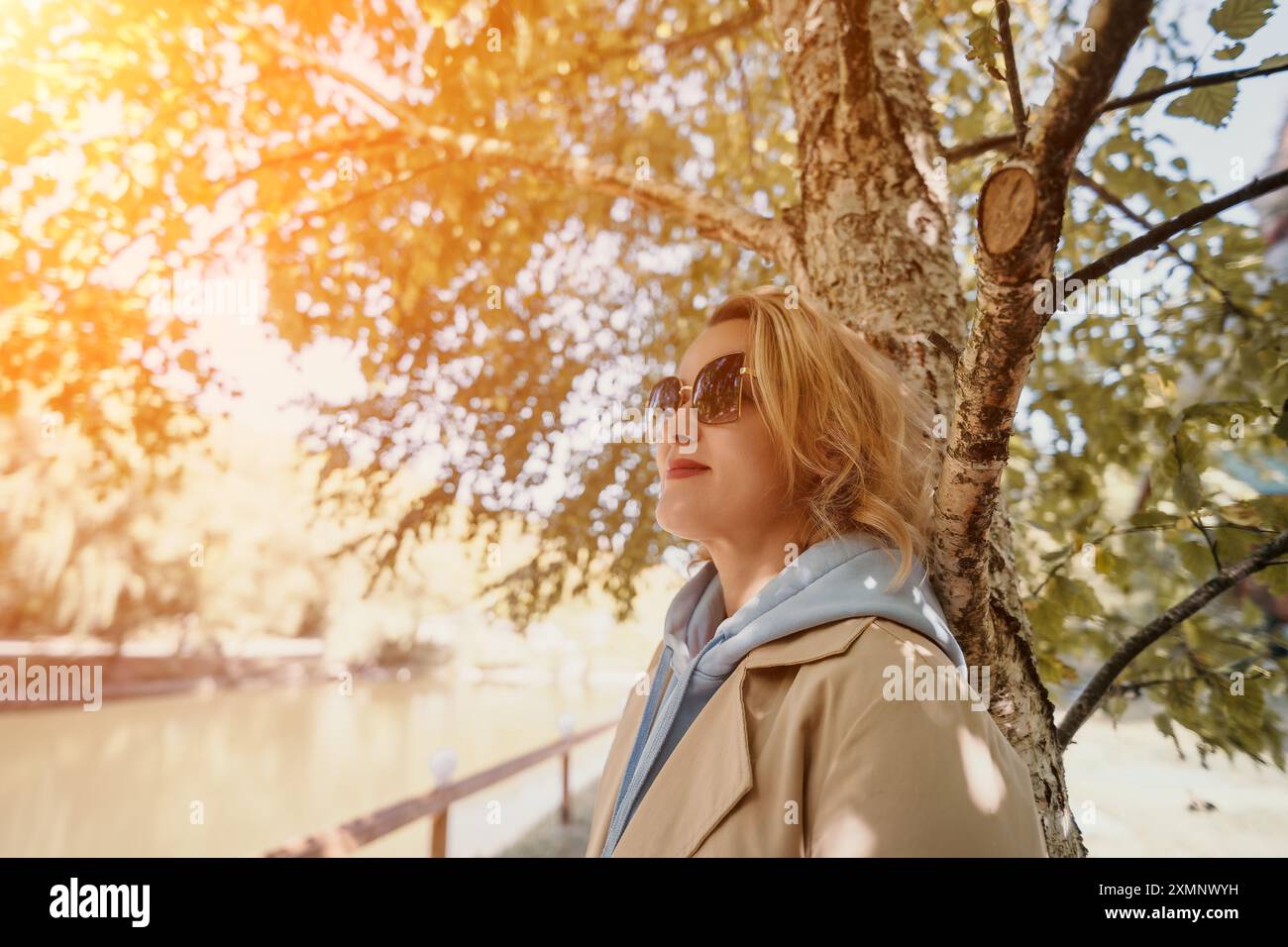 Woman in Sunglasses Leaning Against a Tree Stock Photo