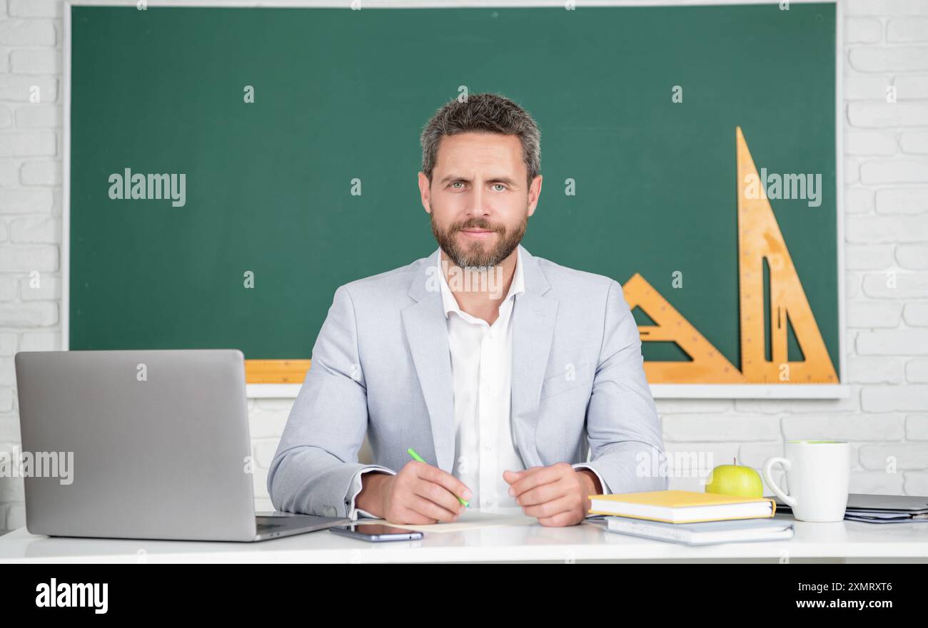 cheerful school teacher in classroom with laptop at blackboard Stock ...