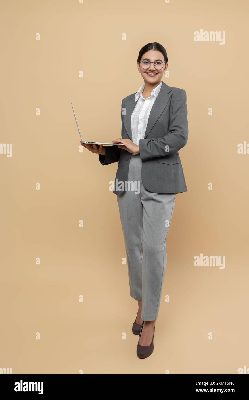 Attractive happy woman in formal wear using laptop for remote work Stock Photo