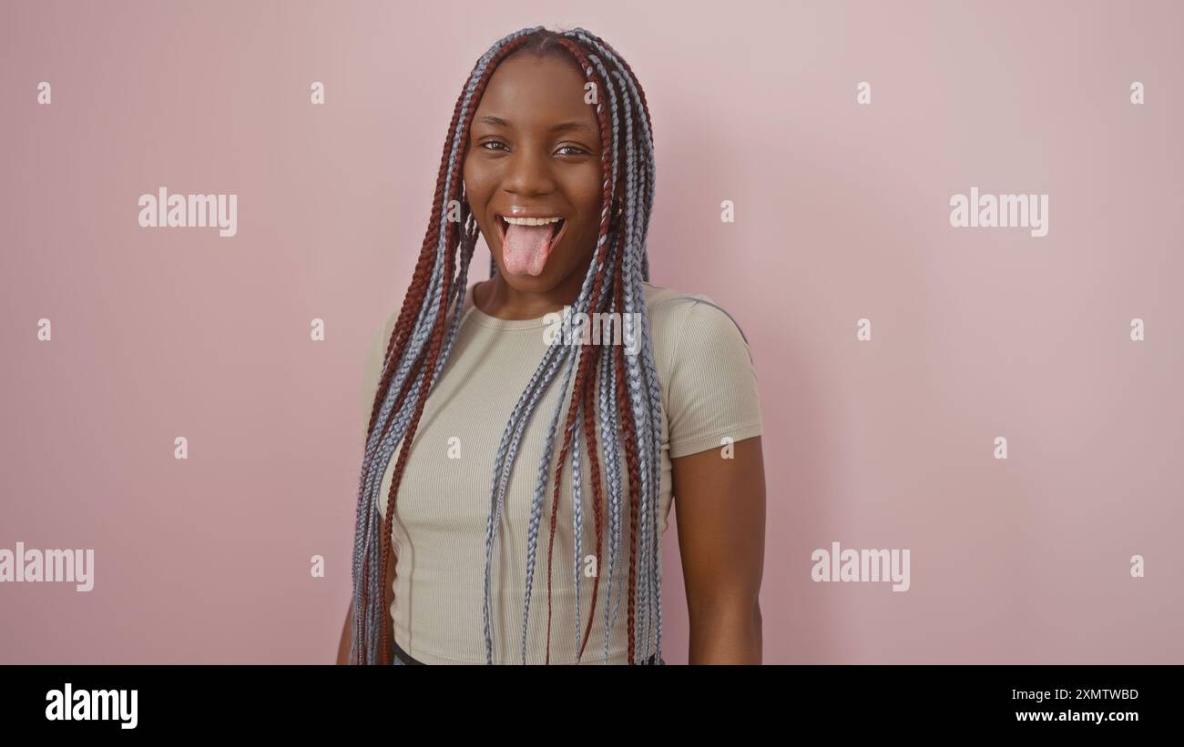 A joyful african american woman with braids sticks out her tongue ...