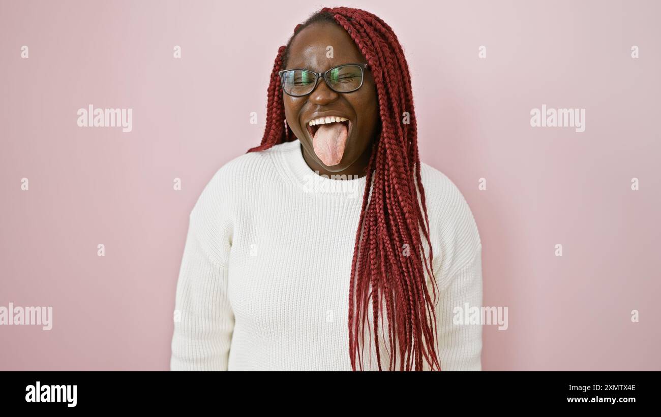 A joyful african american woman with braids sticking out her tongue ...