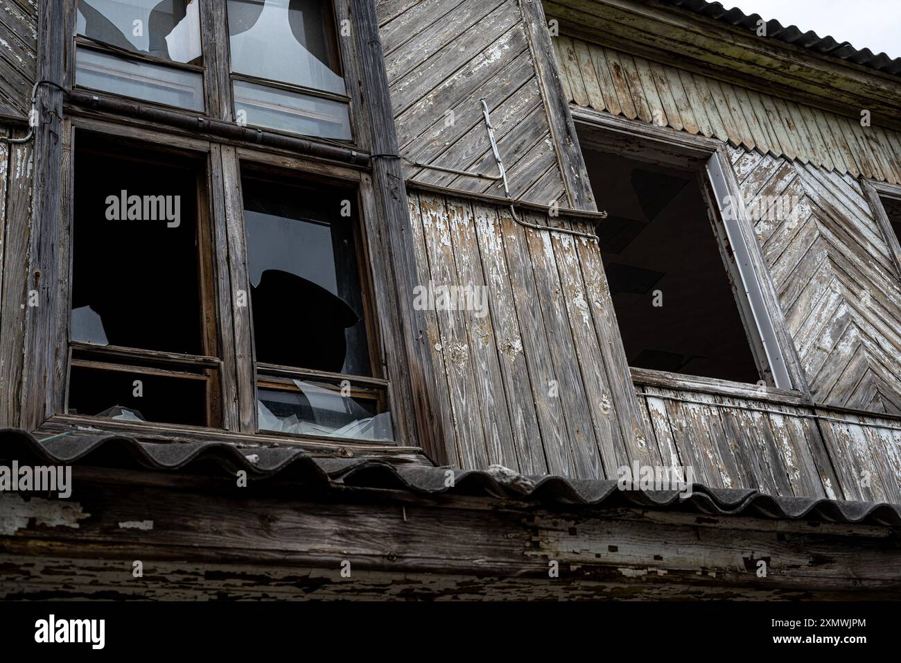 An old abandoned wooden house with damaged windows and a crumbling roof ...