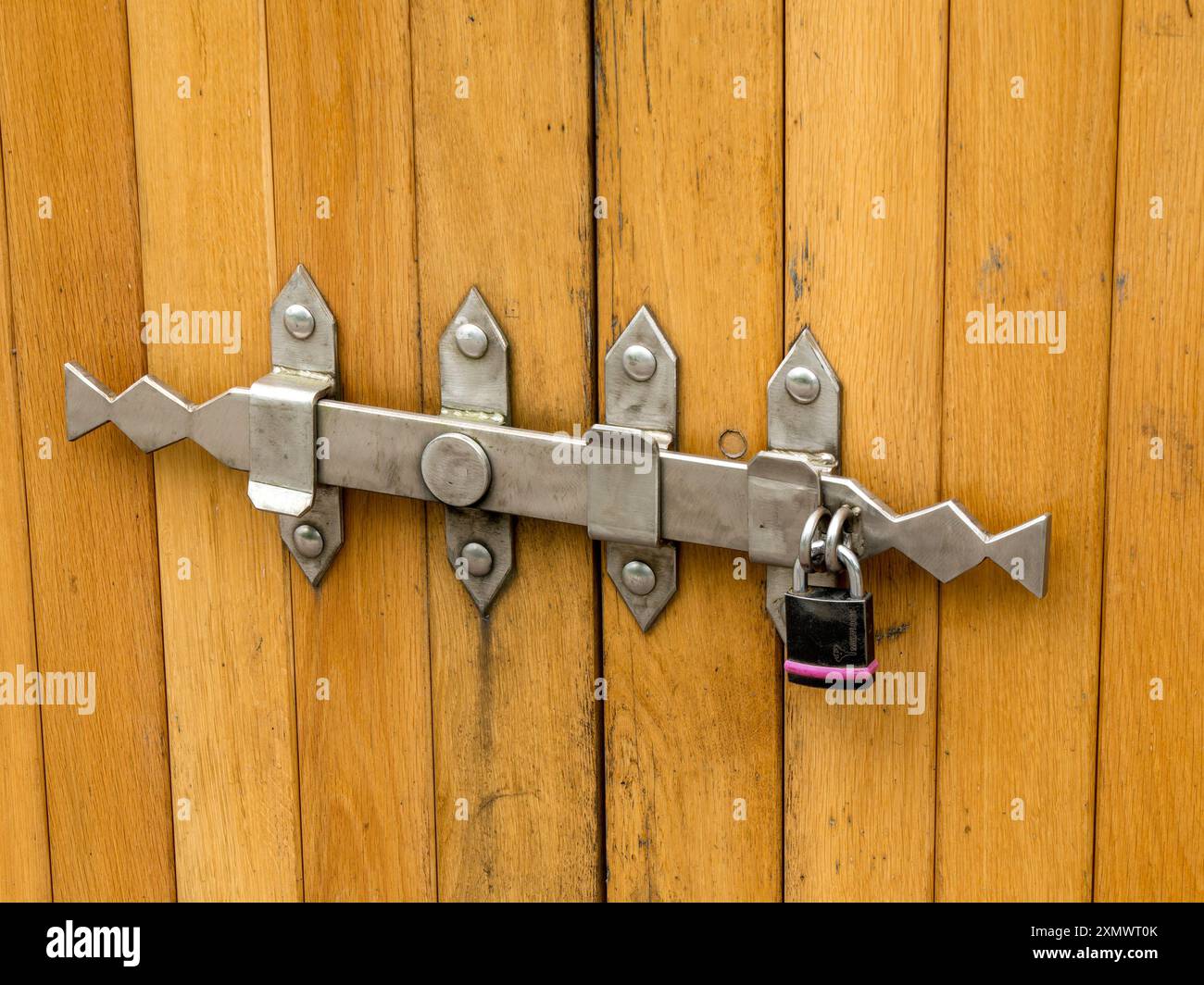 Ornate steel metal latch with padlock on wooden doors, Bradgate park, Leicestershire, England, UK Stock Photo
