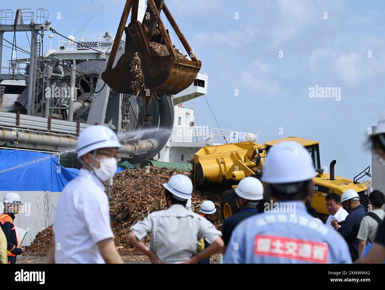 A mountain of Noto Earthquake debris is removed by a crane onto a ...