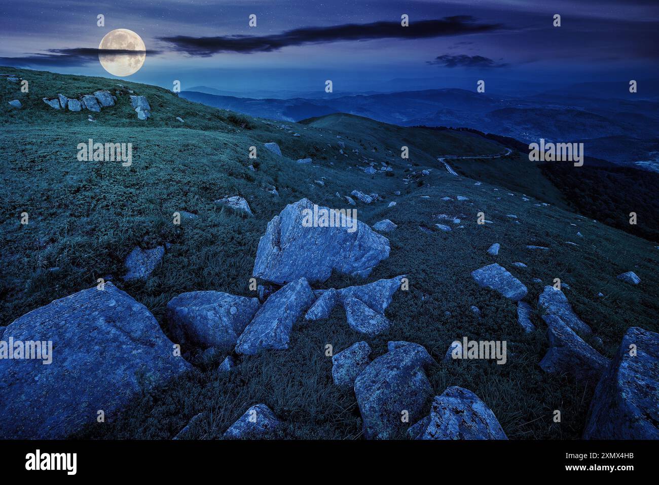 white sharp boulders on the hillside at night. mysterious carpathian countryside scenery in full moon light Stock Photo