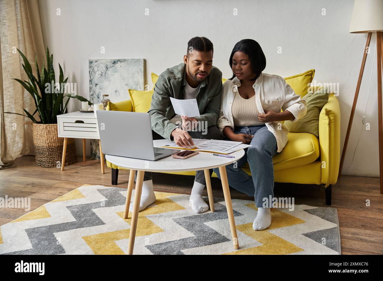 An African American couple review papers and relax on their couch Stock ...