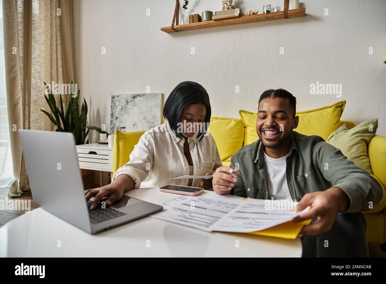 An African American couple sits at a table together, looking at ...