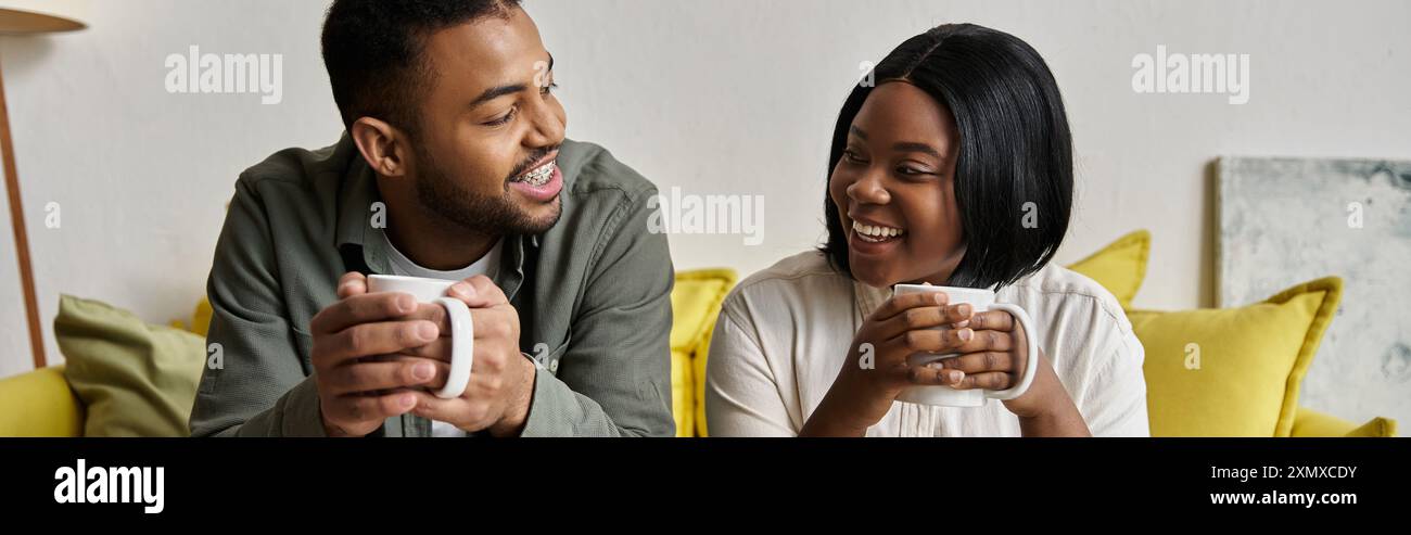 A loving African American couple relaxes on a couch, enjoying coffee ...