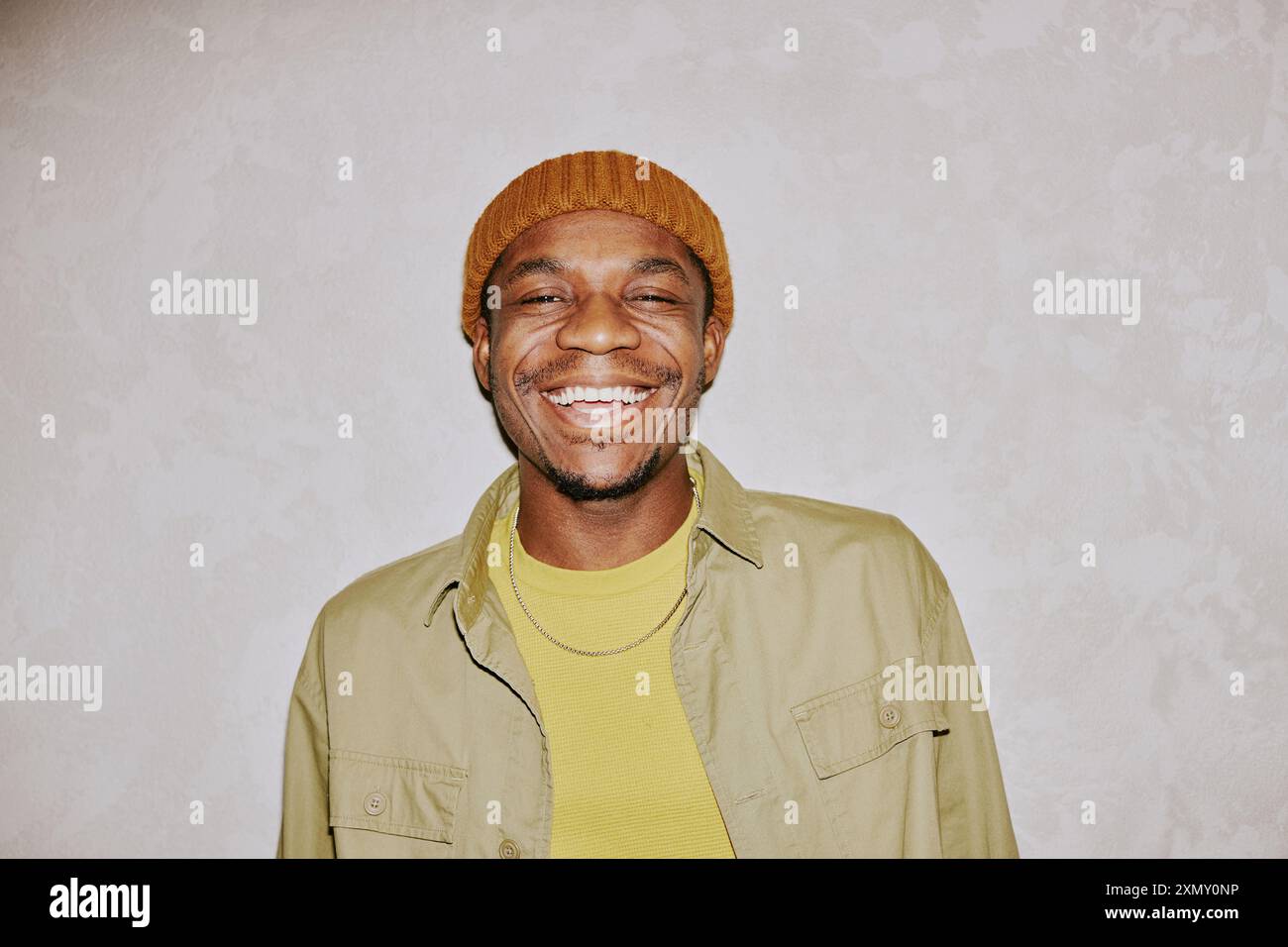 Medium closeup portrait of cheerful young African American man wearing beanie smiling at camera Stock Photo