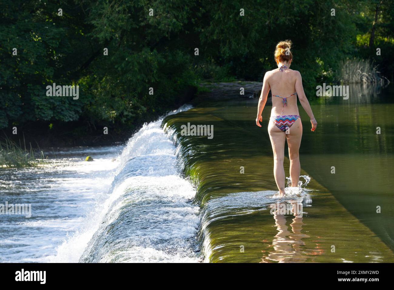 A woman enjoys the water at Warleigh Weir on the River Avon near Bath in Somerset as temperatures soar across the UK. Stock Photo