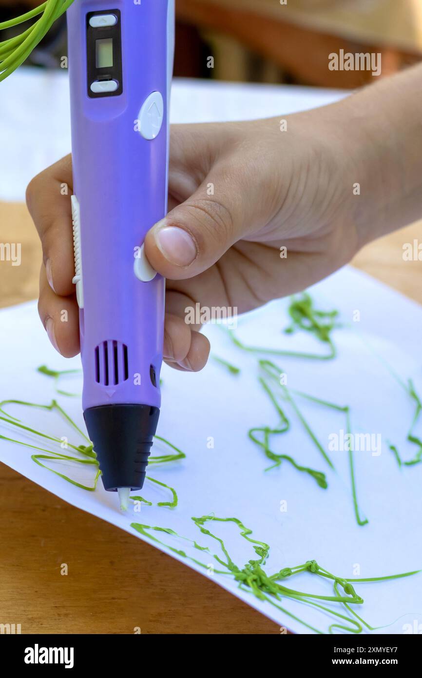 Child's hand creates figures with a 3D pen. Close-up. Stock Photo
