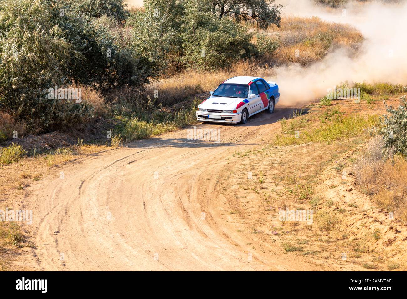 Sharpness Car Rally Sunny summer day. White rally car about to take a sharp turn on a dirt ...