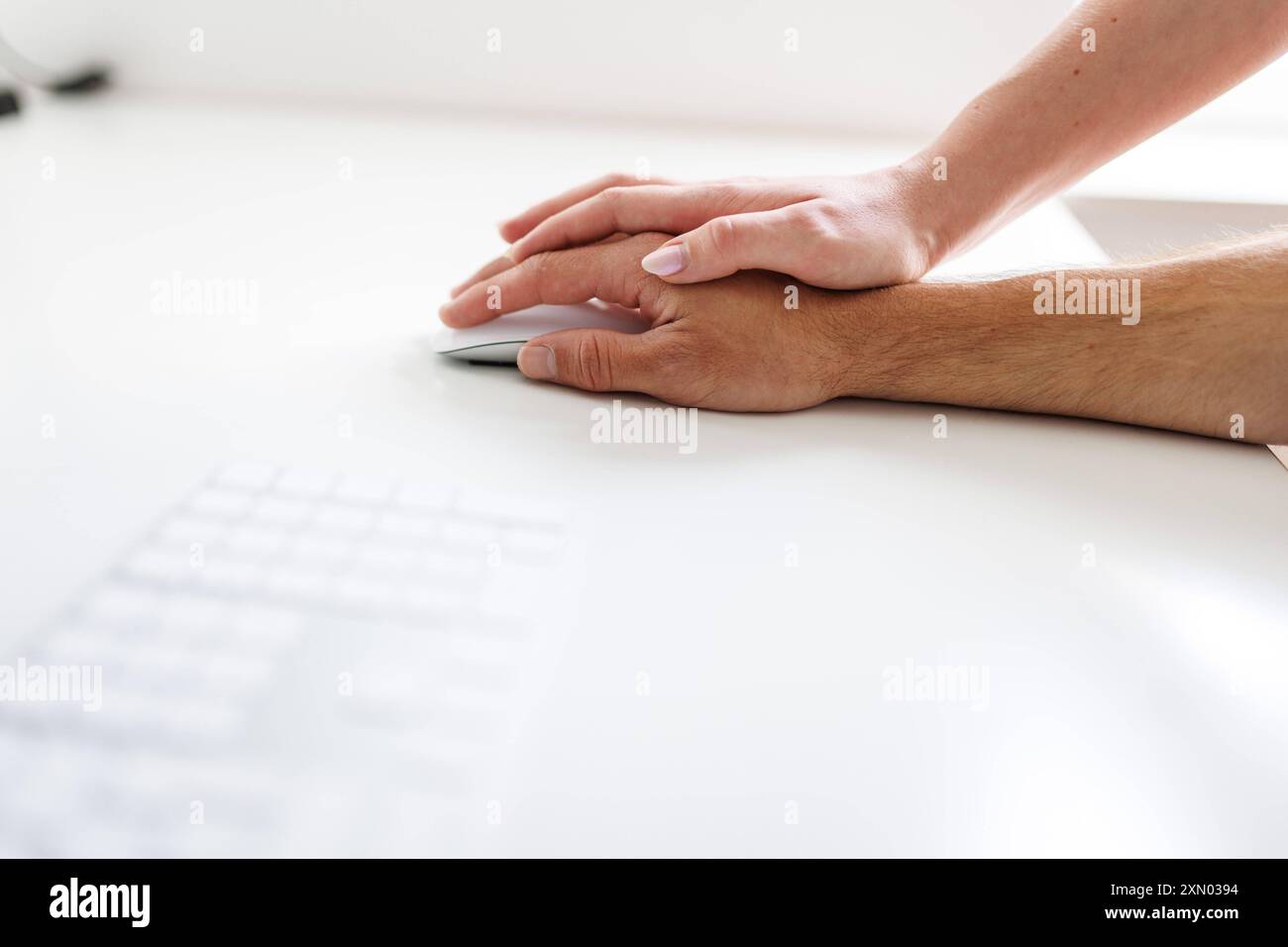 Thema: sexuelle Gewalt am Arbeitsplatz. Die Hand einer Frau liegt auf der Hand eines Mannes an einem Schreibtisch in Berlin, 25.07.2024. Berlin Deutsc Stock Photo