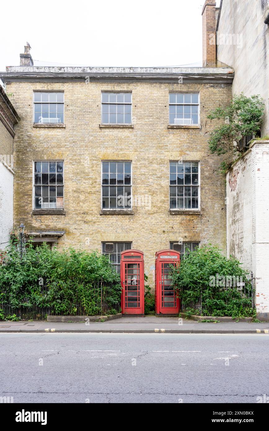 Two red telephone kiosks in front of tall building Stock Photo