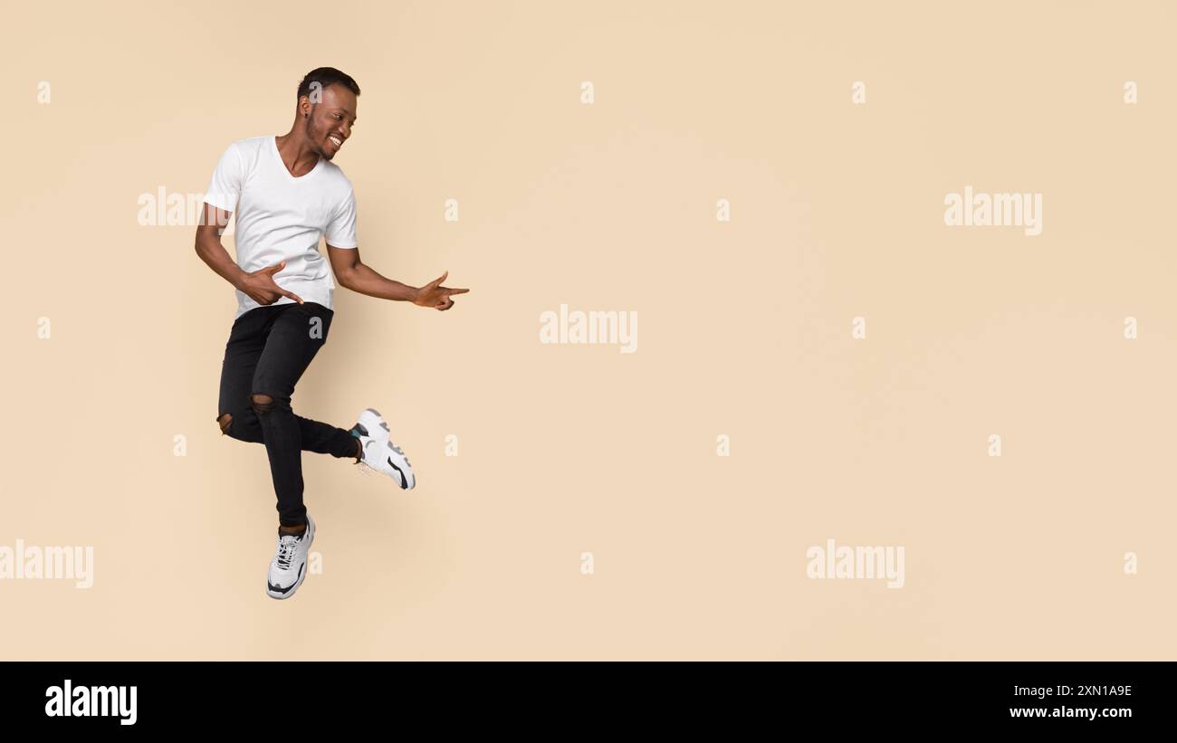 Guy Pointing Fingers Aside Having Fun Over Yellow Background, Panorama Stock Photo