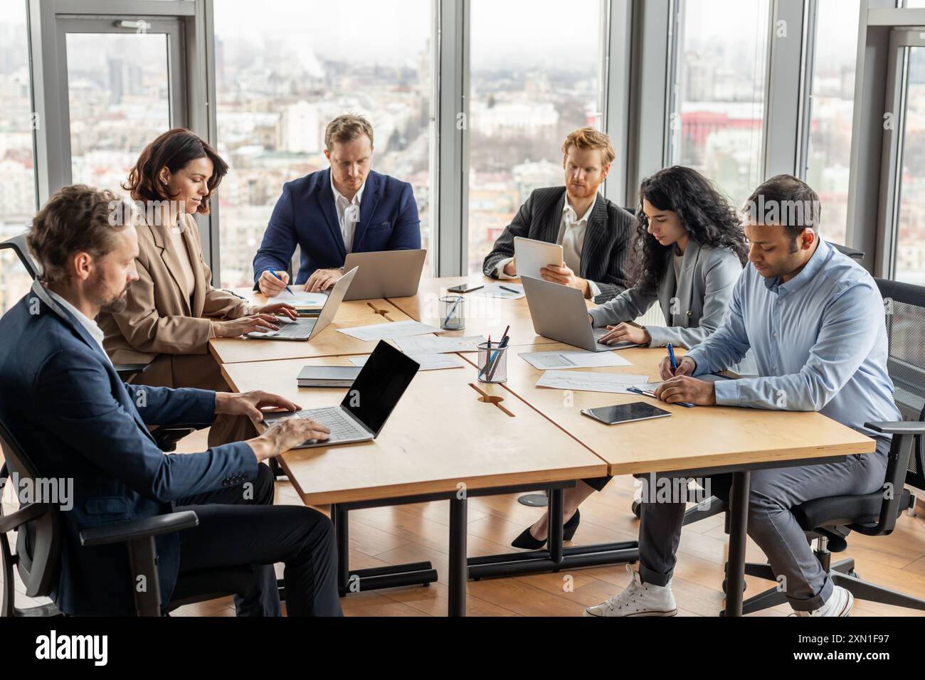 Diverse Team Working on Laptops in Modern Office Setting Stock Photo