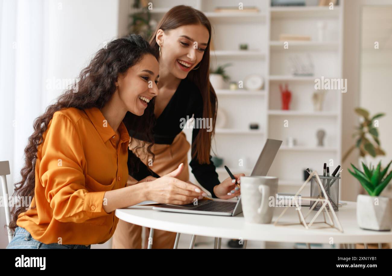 Two Happy Ladies Using Laptop Computer Working Online In Office Stock Photo