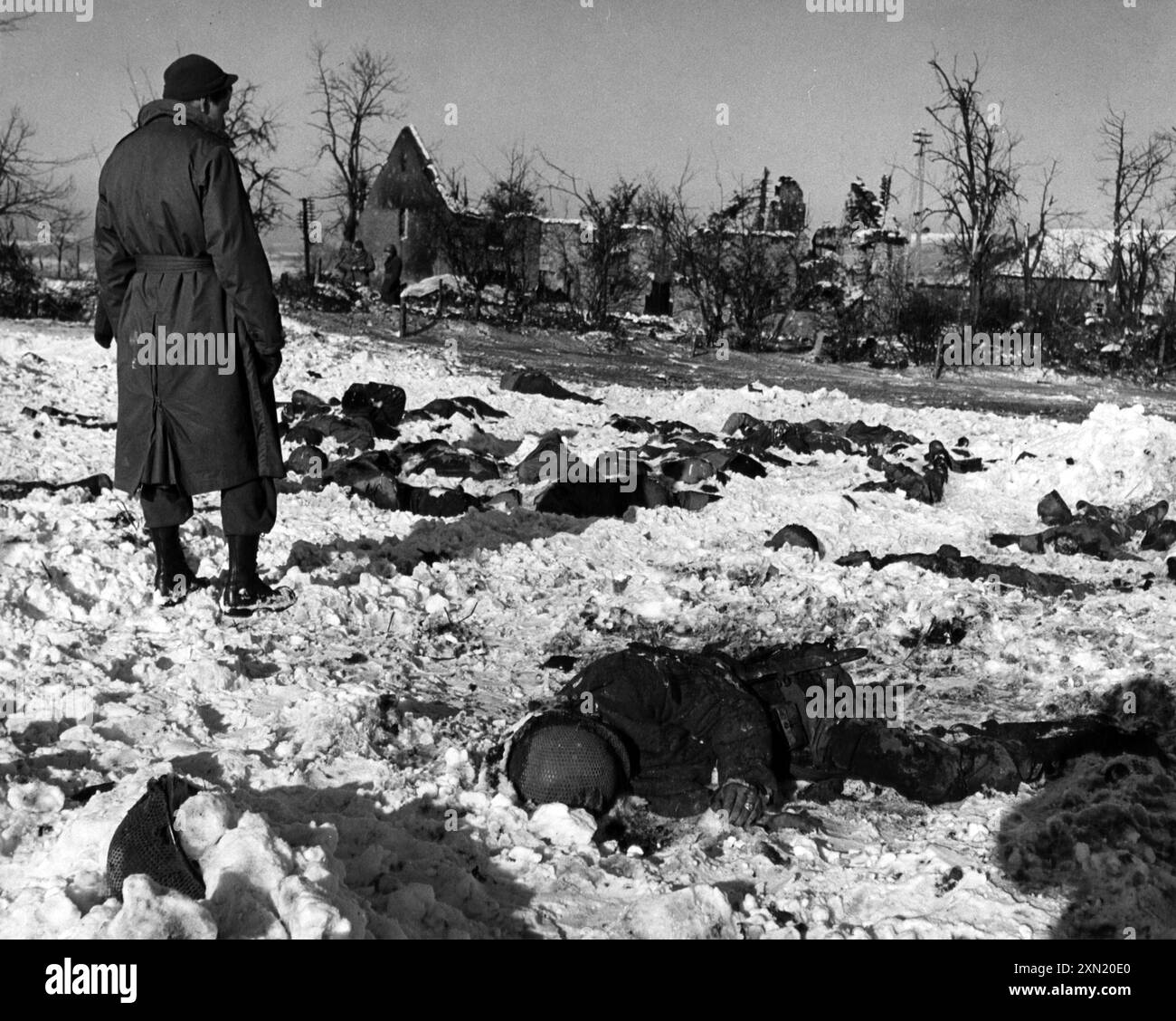 A U.S. soldier observing victims of the Malmedy massacre (17 December 1944), where 84 U.S. prisoners of war were murdered by the Waffen-SS in Belgium, World War Two Stock Photo