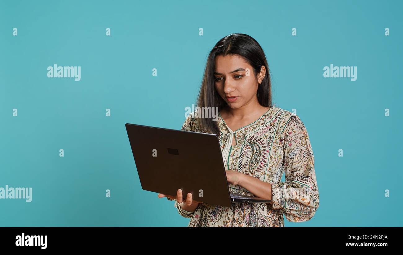Indian woman composing email typing on laptop frustrated with