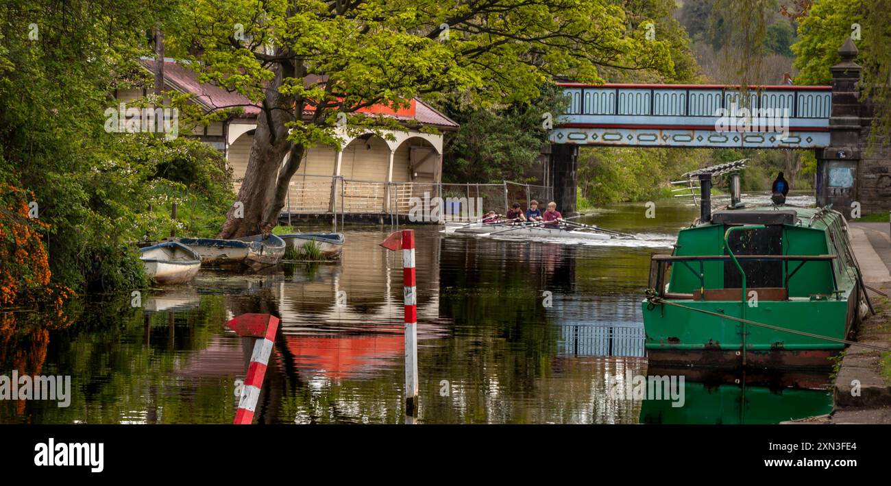 Edinburgh, Scotland, 05.07.2021: Young men rowing a canoe on the Union Canal, next to Ashley Terrace old boathouse, surrounded by greenery with narrow Stock Photo