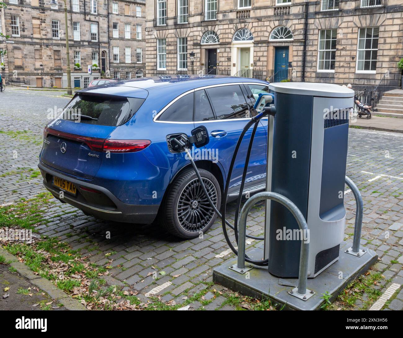 Edinburgh, Scotland, 07.17.2024: Blue Mercedes electric car recharging its batteries on a charging point in a cobbled street in Edinburgh Stock Photo